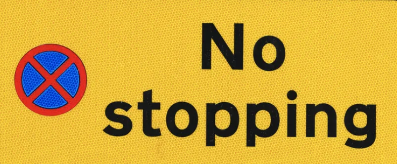 Yellow sign with a prohibition symbol and the words "No stopping".