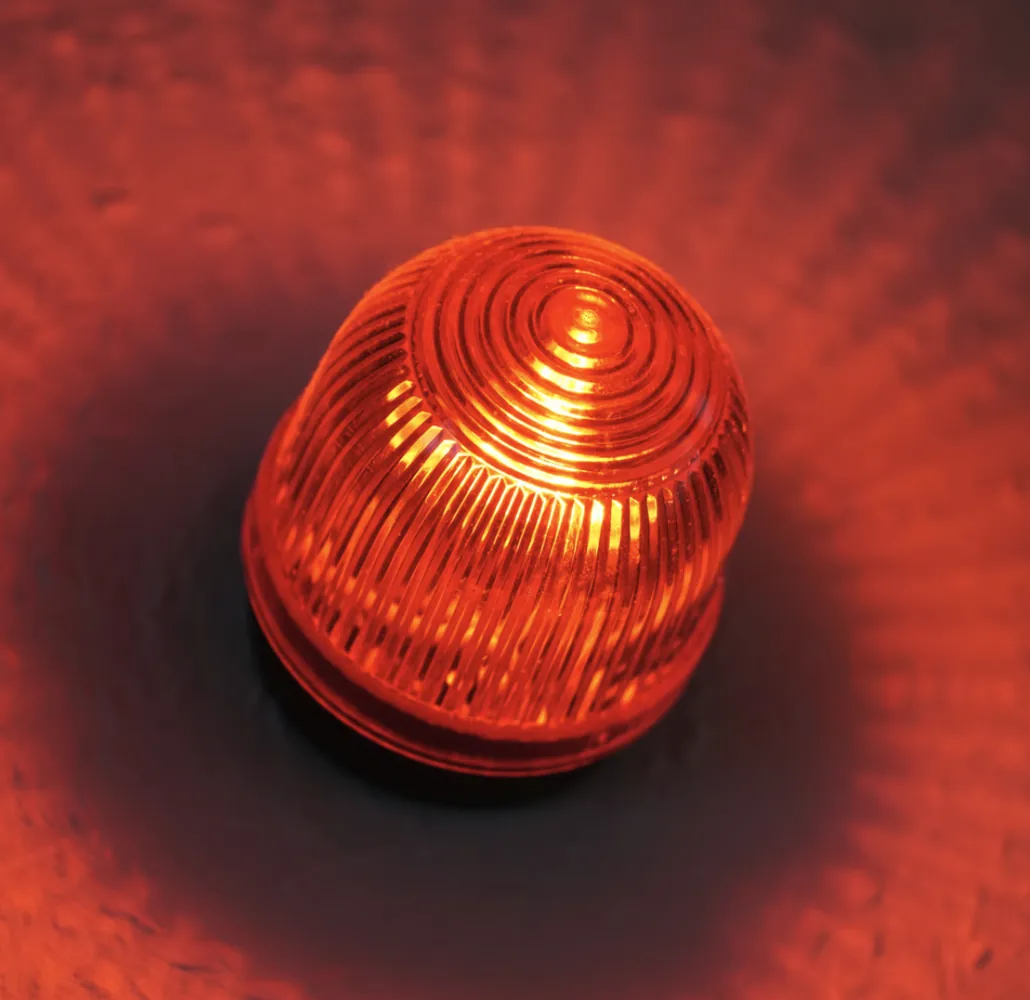 Red warning light glowing in a dark room.