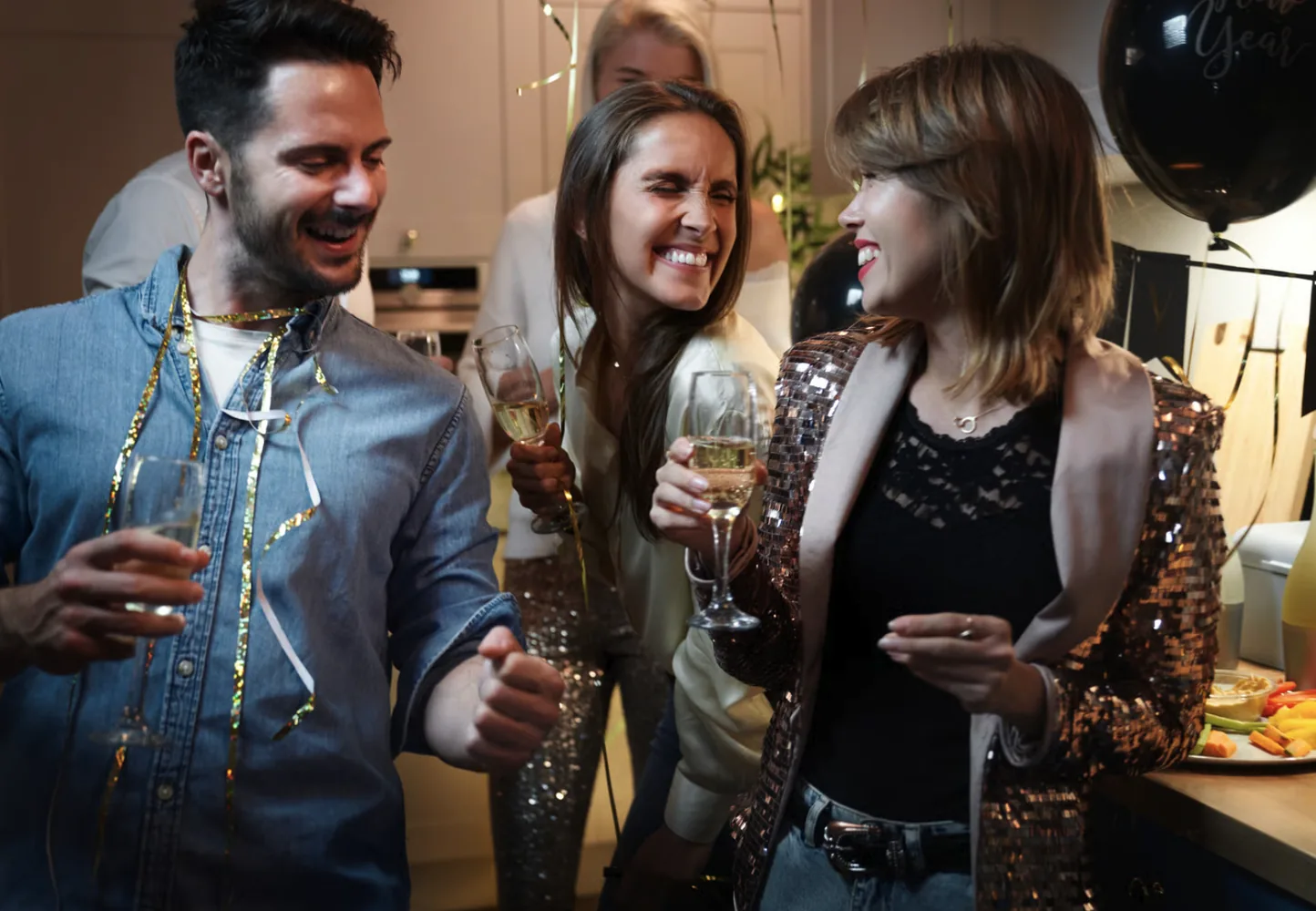 Three colleagues laughing and raising glasses in a bright office space.