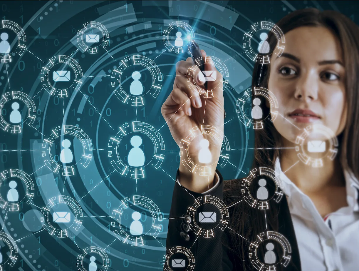 Woman pointing at a digital surface full of icons of people and messages.